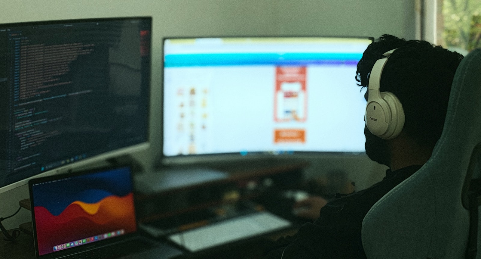 A developer working at a desk with code on multiple monitors